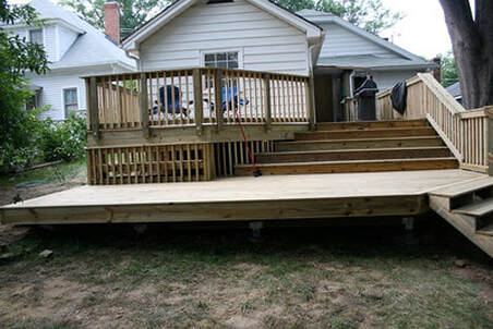 Raised deck with patio and stairs leading up to the home.