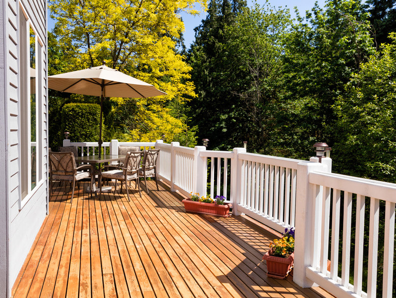 Raised two story deck with white railing and brown wood flooring